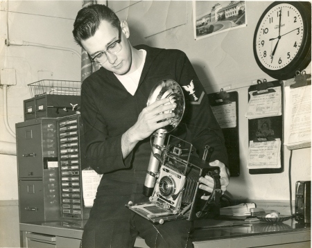Don Cole, US Navy Photographer, PHG-3, shown with US Navy standard issue 4x5' Speedgraphic camera, and flash. US Naval Air Station, Photo Lab, Corpus Christi, Texas, about 1958.